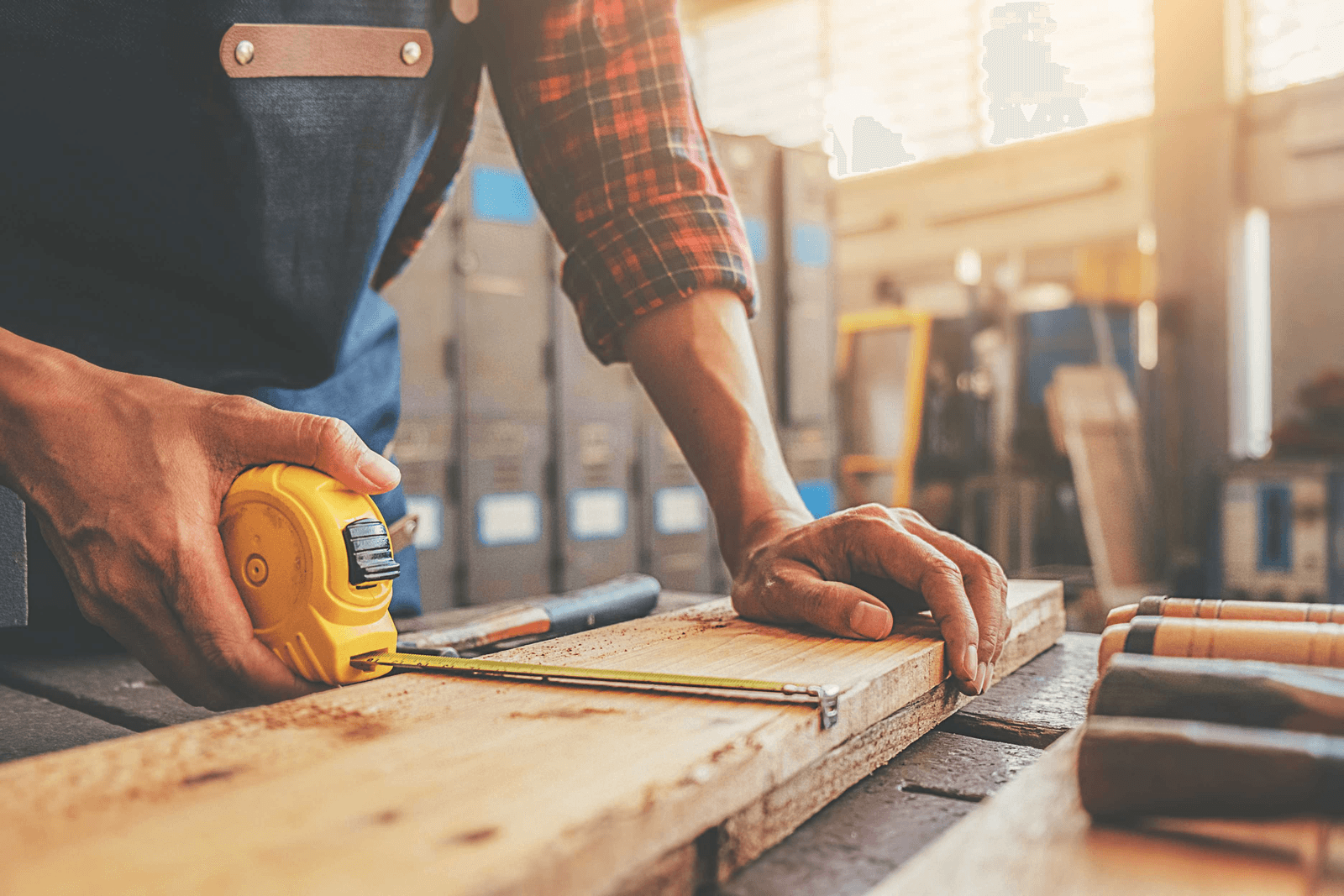 Carpenter measuring timber in workshop